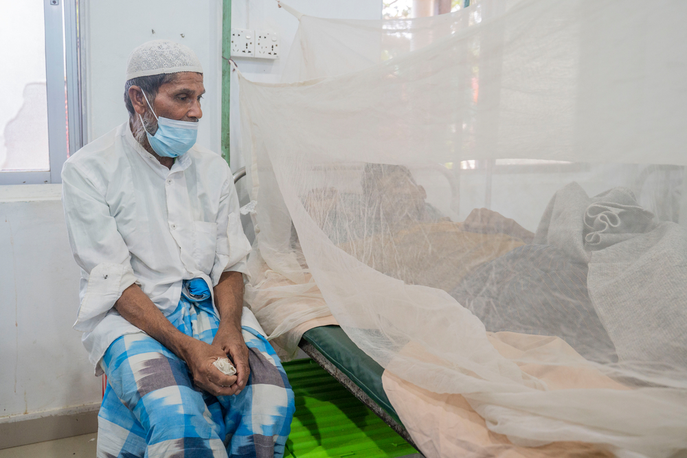 Rohingya father sitting at the bedside of his 21-year-old son, who was admitted to the Doctors Without Borders Kutupalong Hospital with dengue. Bangladesh 2022 © Saikat Mojumder/MSF