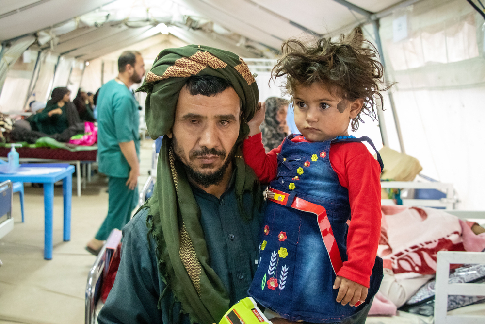 Farhah Din Malik and his daughter inside one of the MSF tents at the Herat Regional Hospital. Farhah Din was in Iran when he received news of the earthquake. Afghanistan, 2023. © Paul Odongo/MSF