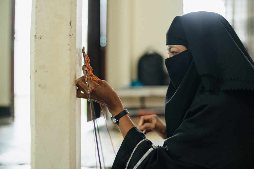 A Rohingya woman weaving a taro leaf artwork as a symbol of the Rohingya refugee experience