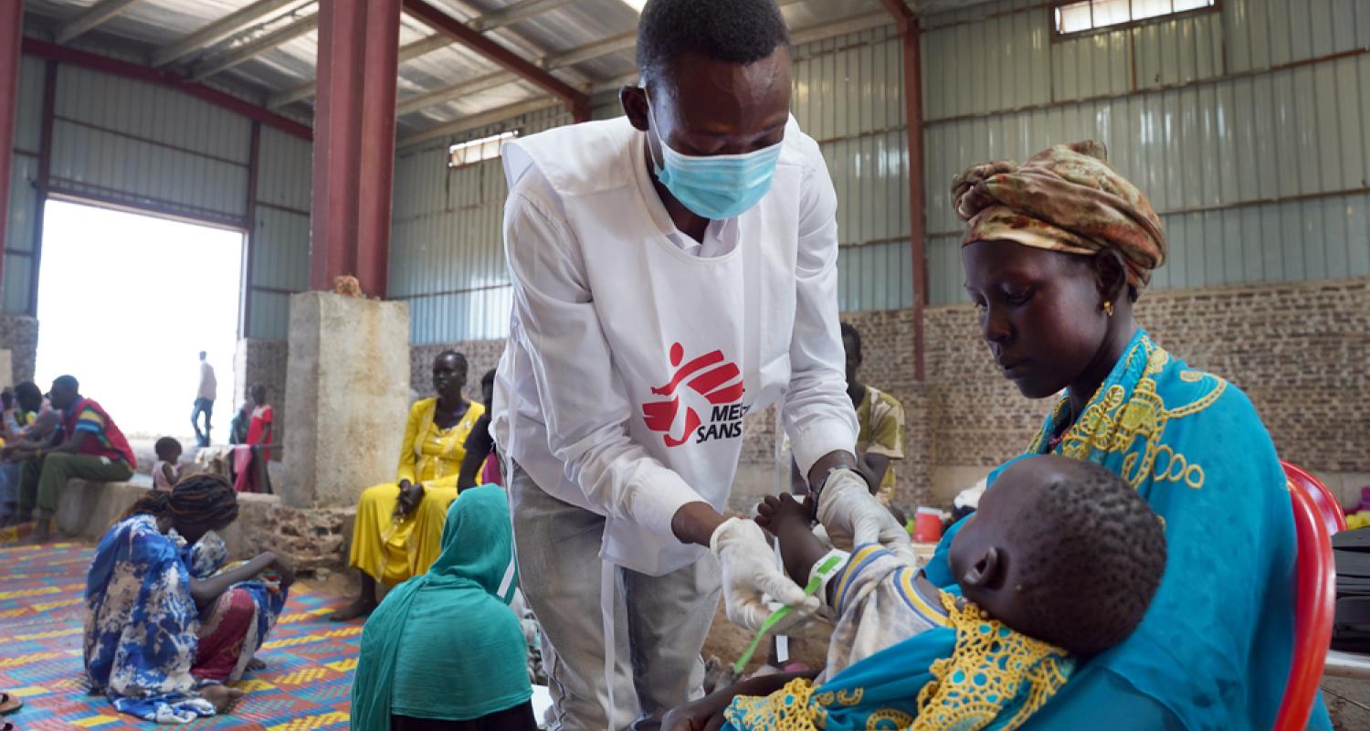 A Doctors Without Borders nurse aide performs the MUAC measurement test on a child during a screening in a Doctors Without Borders mobile clinic at the Riverside transit site in Renk town, Upper Nile State. South Sudan, June 2023. © Nasir Ghafoor/MSF