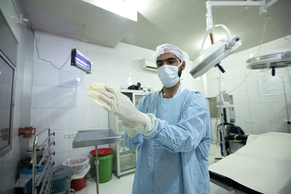 MSF OT nurse, Anwar Saleem, puts on surgical gloves in preparation for a C-section inside the operation theatre managed by MSF at the DHQ Hospital in Timergara, KP, Pakistan on 10th December 2020.