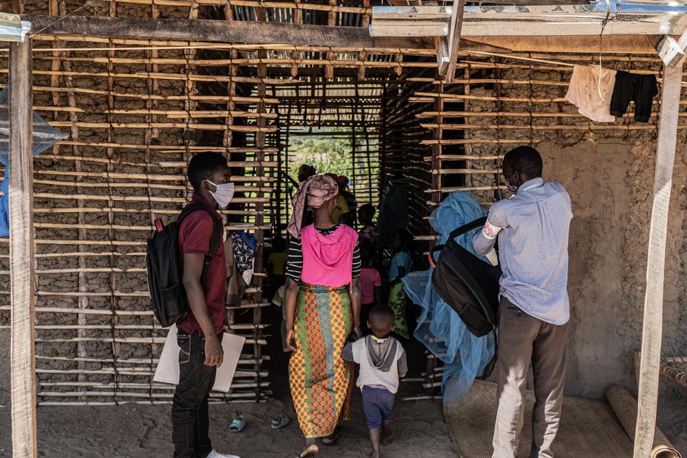 A mental health promoter and a health promoter enter a house which currently houses over 40 people who had fled the armed conflict in Cabo Delgado. 