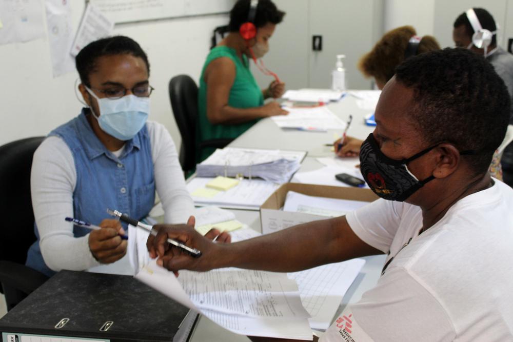 Benita Apa, nurse, explains the patient form to a community health worker.