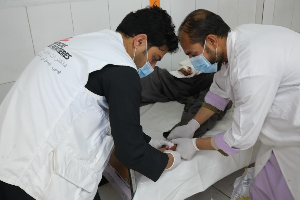 Emergency room supervisor Masood Khan treats a patient for a gunshot wound at the Boost hospital. Helmand province, Afghanista