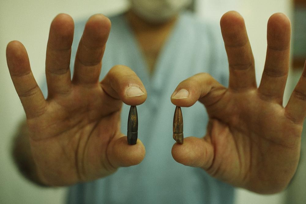Dr. Sebastiano Girmenia, a veteran surgeon who has worked in crisis zone trauma centres for more than twenty years presents two bullets extracted from separate patients at the Médecins Sans Frontières (doctors without borders, MSF) Kunduz Trauma Centre in northern Afghanistan. Photo was taken in 2015. © Andrew Quilty/Oculi 