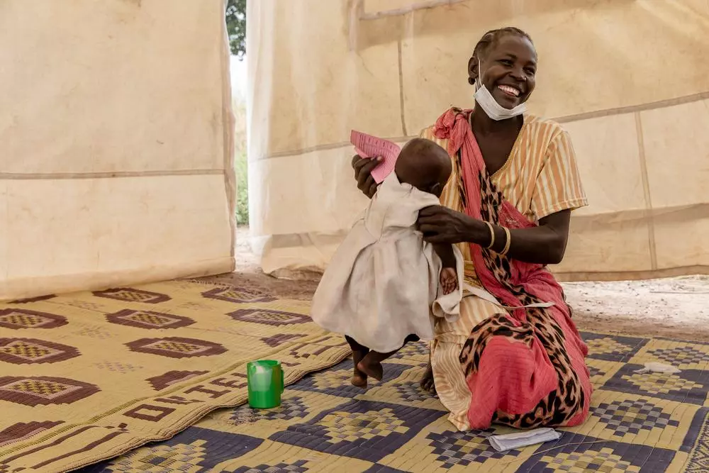 Ateny Mayen Akoi holds her eight-month-old daughter Agel after she received Seasonal Malaria Chemoprevention (SMC) drugs at a distribution site set up in the village of Kuom. South Sudan, 2021. © Adrienne Surprenant/Item 