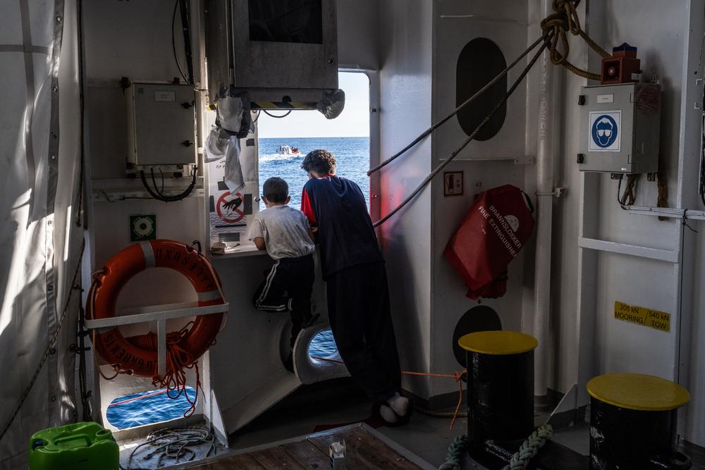 Ali (not real name), 7 years old, and his 18 year-old brother, are looking at the Italian Coast Guard disembarking survivors in Messina Port, Sicily, while waiting for their turn. 