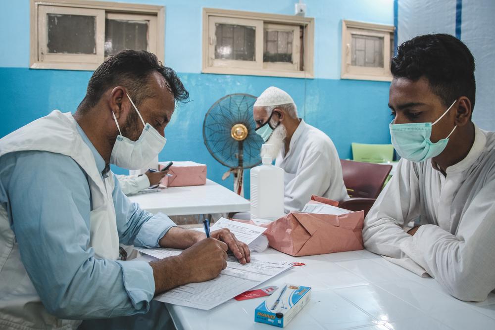 An MSF doctor taking the medical history of someone coming for their COVID-19 vaccination. They check if he has any symptoms of COVID, or is currently taking any medication. Pakistan, 2021. © Pirah Qasi/MS
