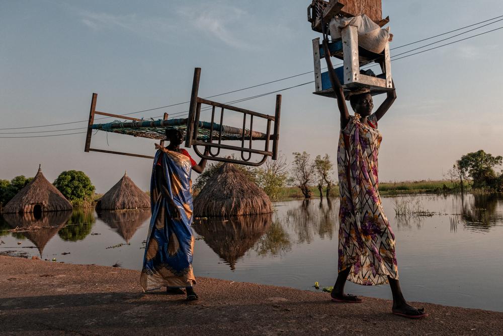 Women carry pieces of furniture and goods in a flooded area of Unity State. Across Unity state people’s homes and livelihoods (crops and cattle), as well as health facilities, schools, and markets, are completely submerged by floodwaters.