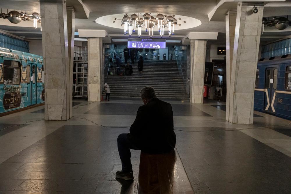 A man sits on a metro bench, between wagons where people now live, hiding fromthe shelling. Kharkiv, Ukraine, April 11, 2022. © Adrienne Surprenant/MYOP 