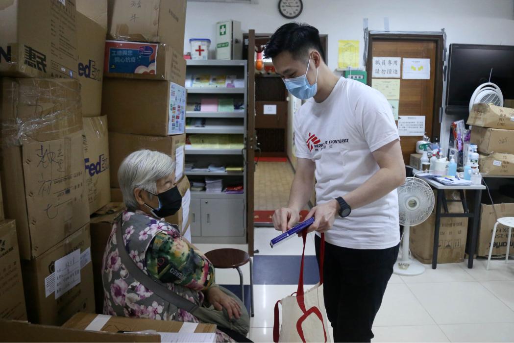 MSF staff shows the patient the rapid antigen test pack information in Hong Kong