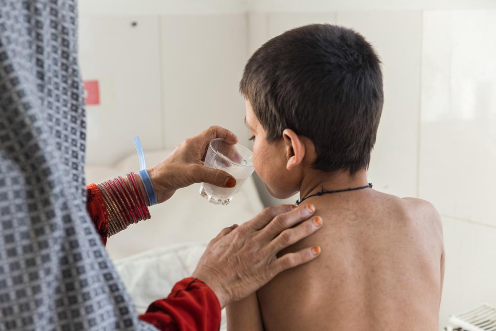  mom is giving a glass of milk to her son Saddiqulah, 10, in the paediatric department of the Doctors Without Borders supported Boost hospital in Lashkar Gah, Helmand province.