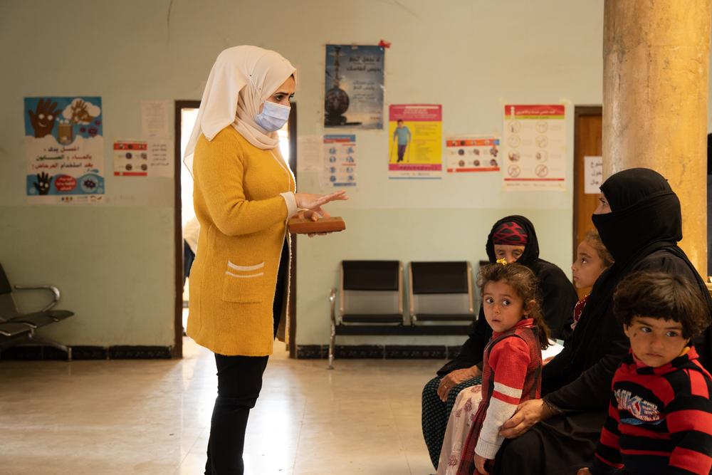 MSF mental health promotion team member conducting a health promotion session with a group of women and their children