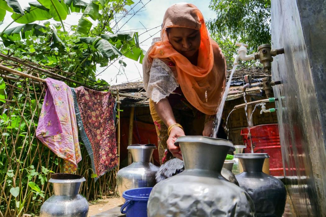 A Rohingya woman fills a pot with drinking water at a water point in Kutupalong-Balukhali camp in Cox’s Bazar district. Bangladesh, July 2022. © Elizabeth Costa/MSF