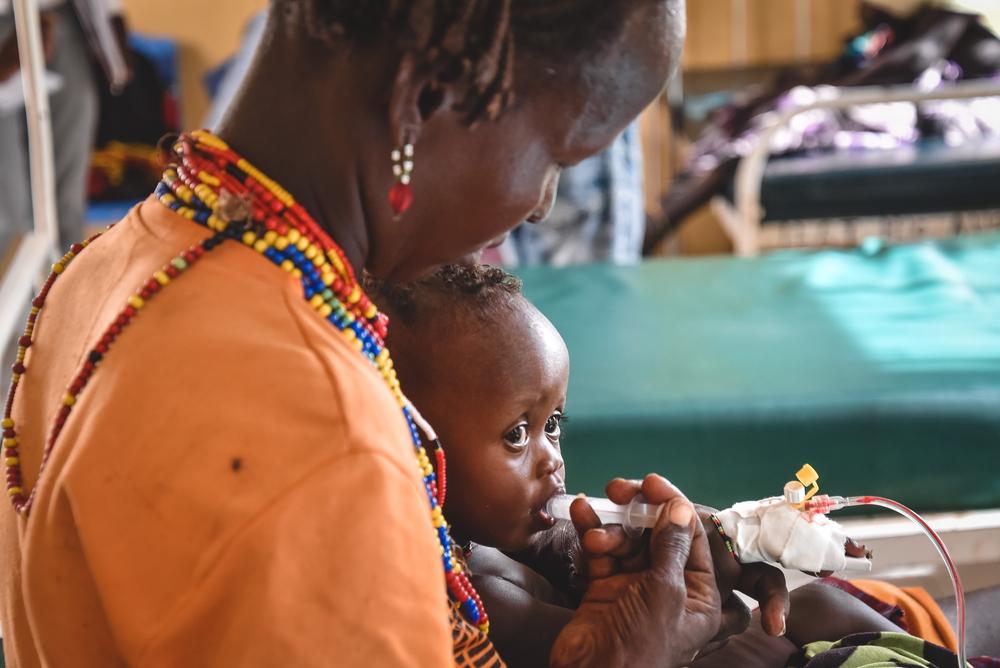 A mother feeds her nine month old daughter milk through a syringe at the Inpatient Therapeutic Feeding Center(ITFC) in Illeret Health Center. Kenya, 2022. © MSF/Lucy Makori