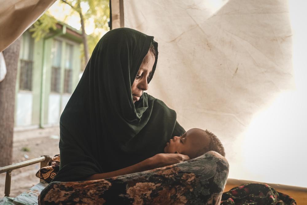 A mother watches on as her son takes a nap in the inpatient therapeutic feeding centre tent. Ethiopia, 2022. © Njiiri Karago/MSF
