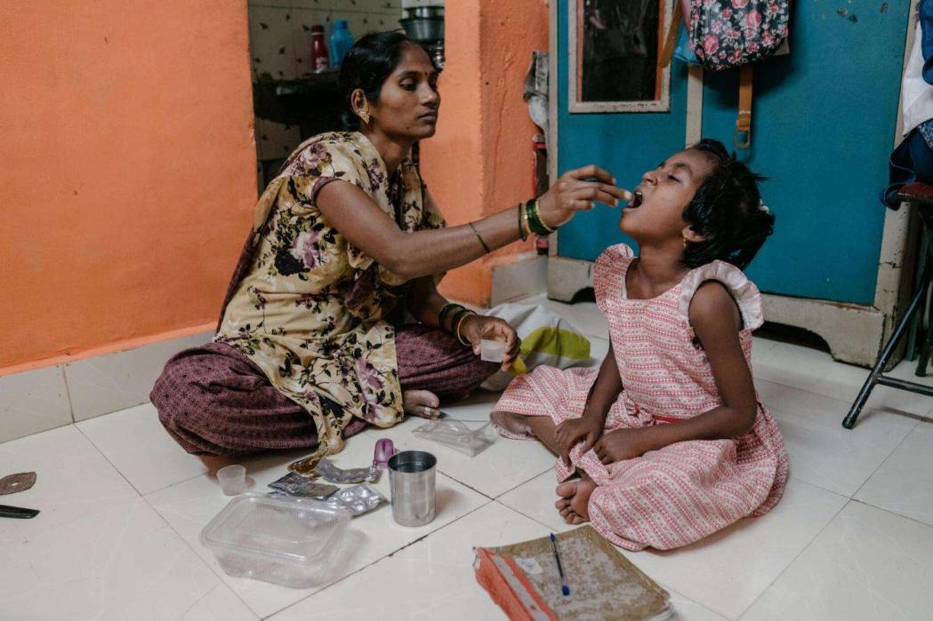 A 7-year-old DRTB (Drug Resistant​ Tuberculosis) patient being given her TB medication by her mother.​ India, February 2022. © Prem Hessenkamp