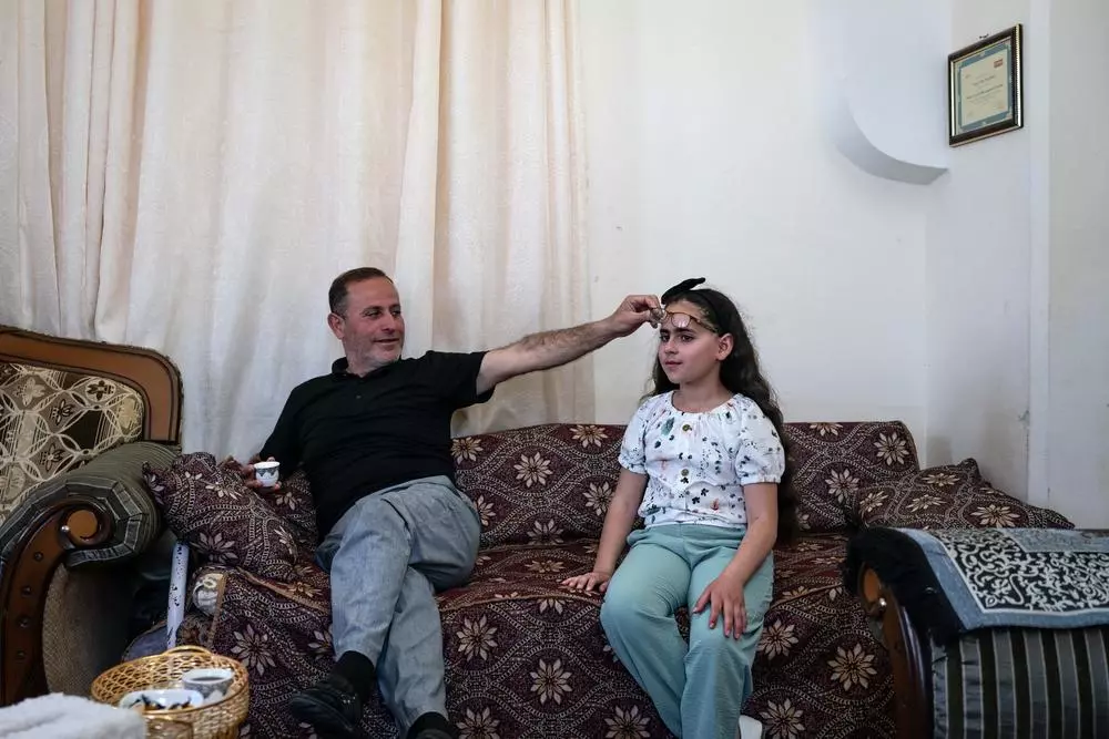 Yasser Abu Markhiyeh shows his daughters eye damaged during a settler attack when she was an infant, in his home in Hebron. Palestine, May 2023. © Samar Hazboun