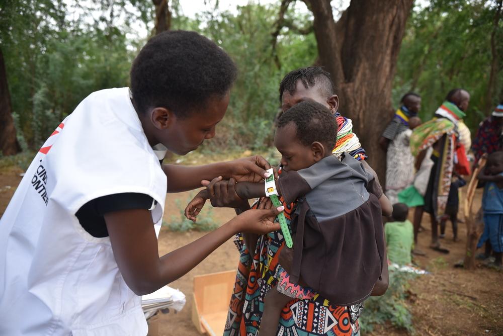 Doctors Without Borders nutritionist measures the mid- upper arm circumference (MUAC) of a child to help identify cases of malnutrition during an outreach activity in Lodakach Ward. Kenya, July 2023. © MSF/Lucy Makori