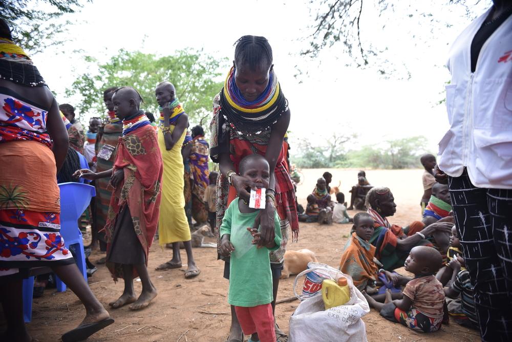 A mother feeds her two year old son with supplementary food given after a nutrition review during a medical outreach in Lodakach. The son has severe acute malnutrition and her sister and brother both have measles and malaria. Kenya, July 2023. © MSF/Lucy Makori