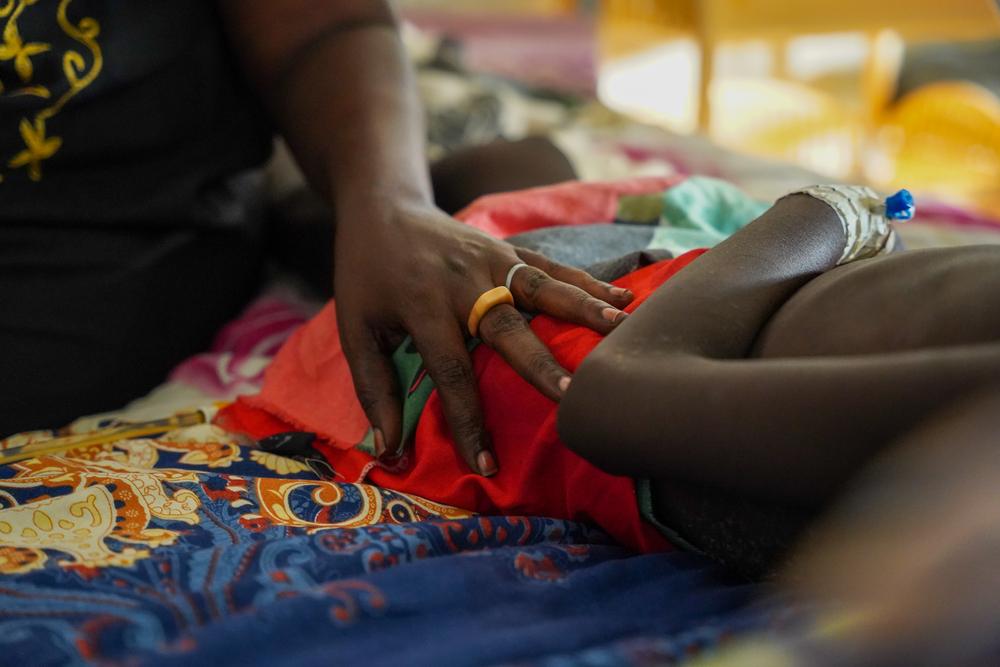 An aunt calms her 9-year-old niece as she is admitted to the paediatric ward for other medical complications after recovering from measles at Doctors Without Border hospital in displacement camp in Bentiu, Unity state. South Sudan, July 2023. © Nasir Ghafoor/MSF