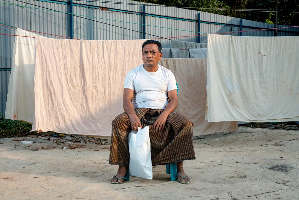 Habibullah, 52, sits, holding a bag with his essential documents: identification, official certificates, and driver's license.