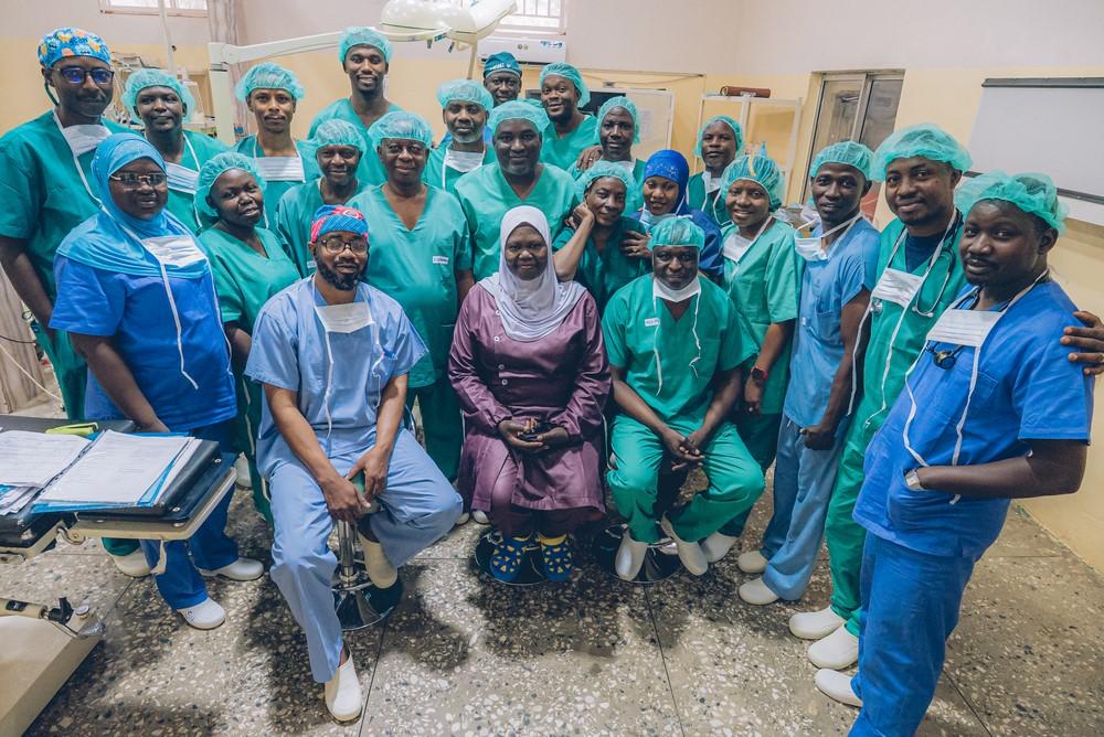 A team of highly trained plastic and maxillofacial surgeons, anaesthesiologists and nurses pose for a photo at the Sokoto Noma hospital. Four times a year, the team perform life-changing reconstructive surgery for survivors of Noma, a bacterial disease that can result in severe disfigurement. Sokoto, Nigeria, May 2023. © Fabrice Caterini/INEIDIZ