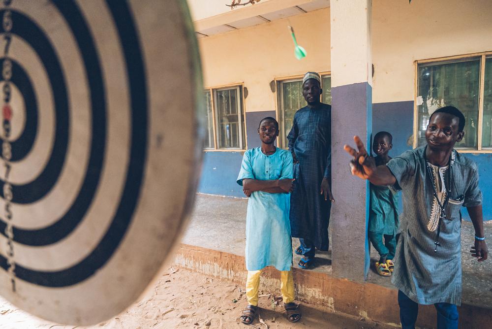 Rabiu (right), a Noma survivor, plays darts in the courtyard of the Sokoto Noma hospital. Rabiu received reconstructive surgery from an MSF medical team. Sokoto, Nigeria, May 2023. © Fabrice Caterini/INEDIZ 