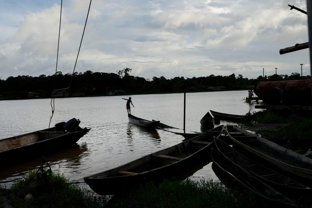 A boy balances on the end of a canoe near an indigenous community on the banks of the Orinoco River. Mobility in the area is only by river, and it can take hours or even days to reach medical care. Delta Amacuro state, Venezuela, May 2023. © Matias Delacroix