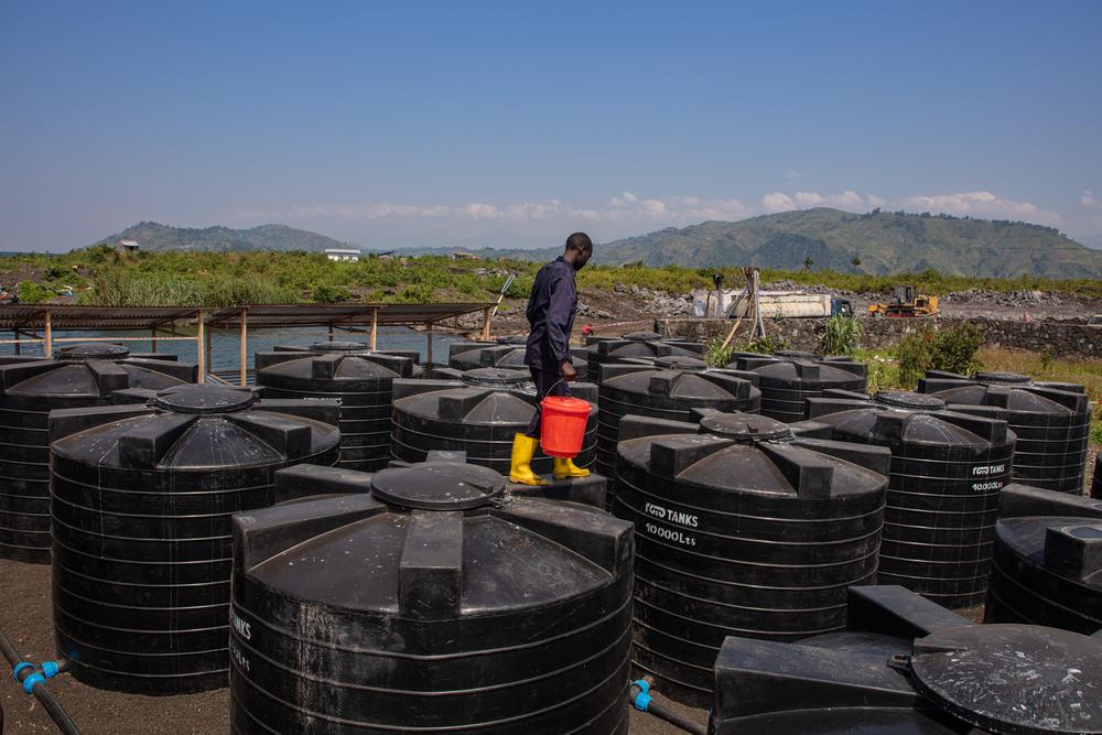 An MSF water and sanitation hygienist walks across the top of water tanks being used to store and treat water for the people living in Bulengo displaced people’s camp. Goma, North Kivu province, Democratic Republic of Congo, July 2023. © Alexandre Marcou/MSF