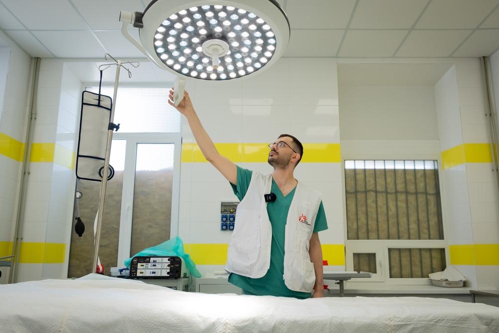 Dr Khassan El-Kafarna, an MSF doctor, adjusts the light in the operating room of Kostiantynivka hospital. MSF teams transformed the hospital’s ground floor pharmacy into an operating room, to respond to a steep increase in shelling and, consequently, an increase in the number of patients requiring urgent surgery. Donetsk oblast (province), Ukraine, June 2023. © Linda Nyholm/MSF