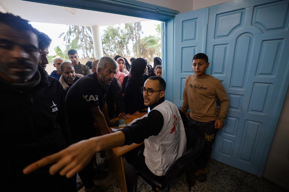 Doctors Without Borders health worker attends people at the waiting area in Al-Shaboura clinic.