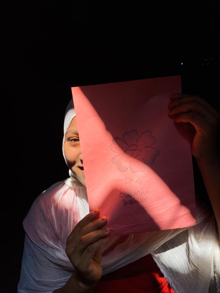Sawmira, 12, holds up one of her drawings. Cox’s Bazar, Bangladesh, October 2023 © Ishrat Bibi