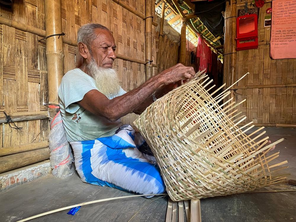 Nur Mohammad, 79, crafts chicken coops out of bamboo. A former soldier, he struggles to earn enough money to make up for inadequate food rations and feed his family of six. Cox’s Bazar, Bangladesh, October 2023 © Ishrat Bibi 