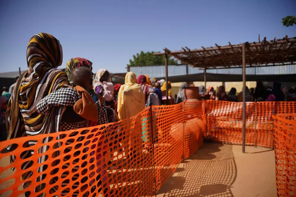 Mothers and children wait in a queue at Doctors Without Borders clinic in Zamzam camp. Sudan, February 2024. © Mohamed Zakaria 