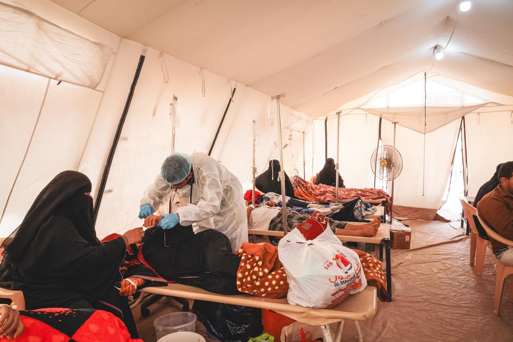 Medical team inside one of the cholera treatment centre’s tent providing medical care for a patient. Yemen, May 2024. © Athmar Mohammed/MSF
