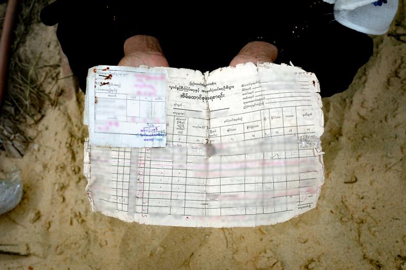 A Rohingya refugee holds up a Household Registration Card, issued by Myanmar's Immigration and Population Department.