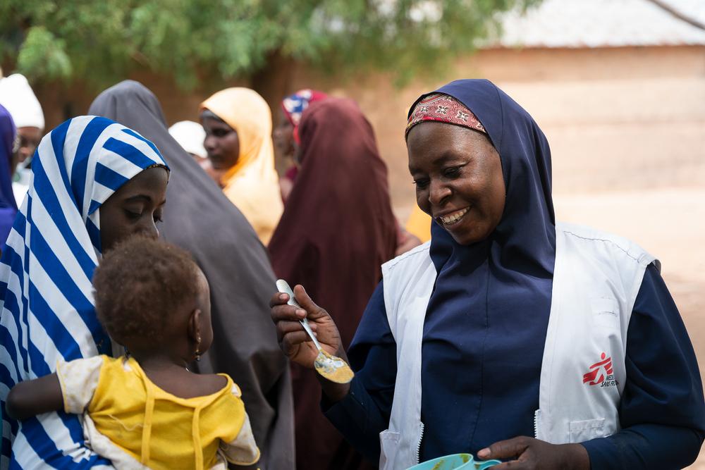 MSF health promotion supervisor in Kebbi, gives a spoon of Tom Brown to a child during a recipe demonstration in Maishaka village, Kebbi State, North West Nigeria.