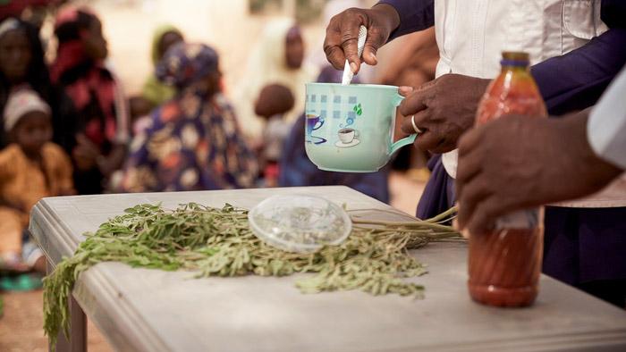 MSF health promotion supervisor in Kebbi, holds a cup during a Tom Brown recipe demonstration