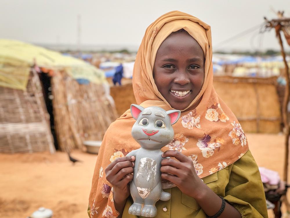 A Sudanese girl holding a toy in her arms. Going to school is what she misses the most while living in the refugee transic camp in Chad. Chad, July 2024. © Thibault Fendler/MSF