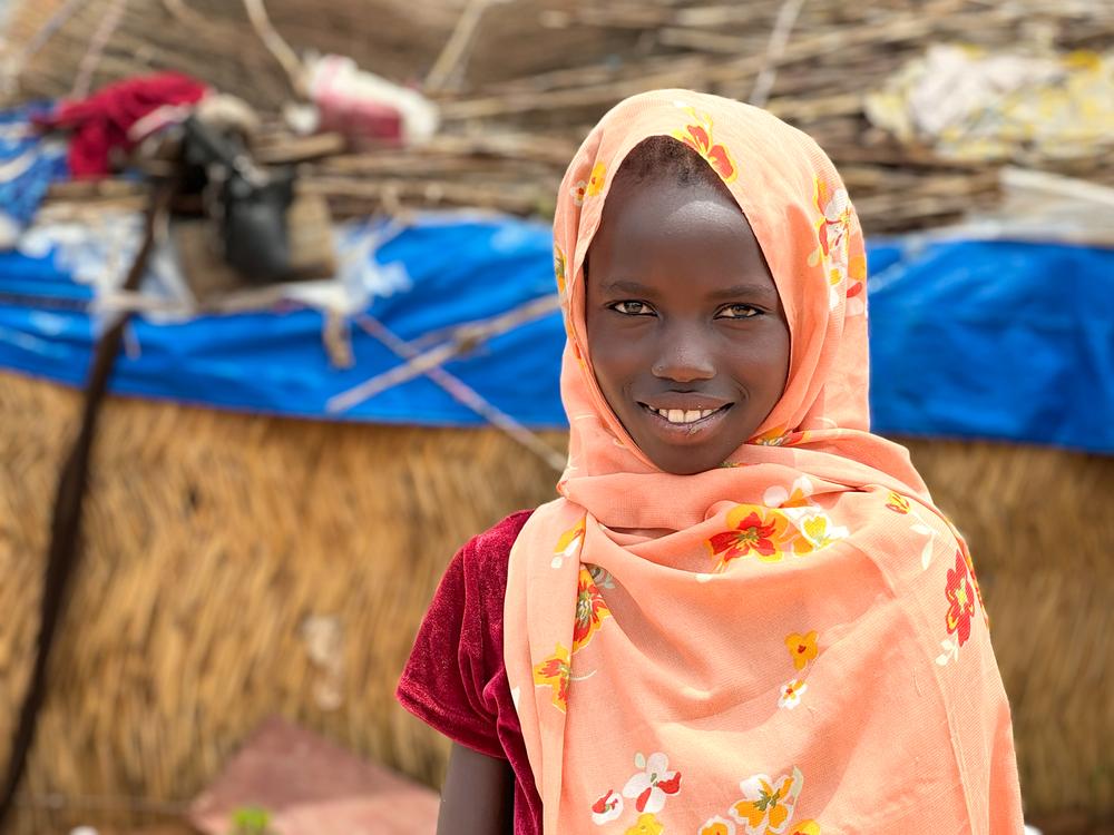 A Sudanese girl poses in front of a makeshift in refugee camp in Adre. Chad, July 2024. © Thibault Fendler/MSF