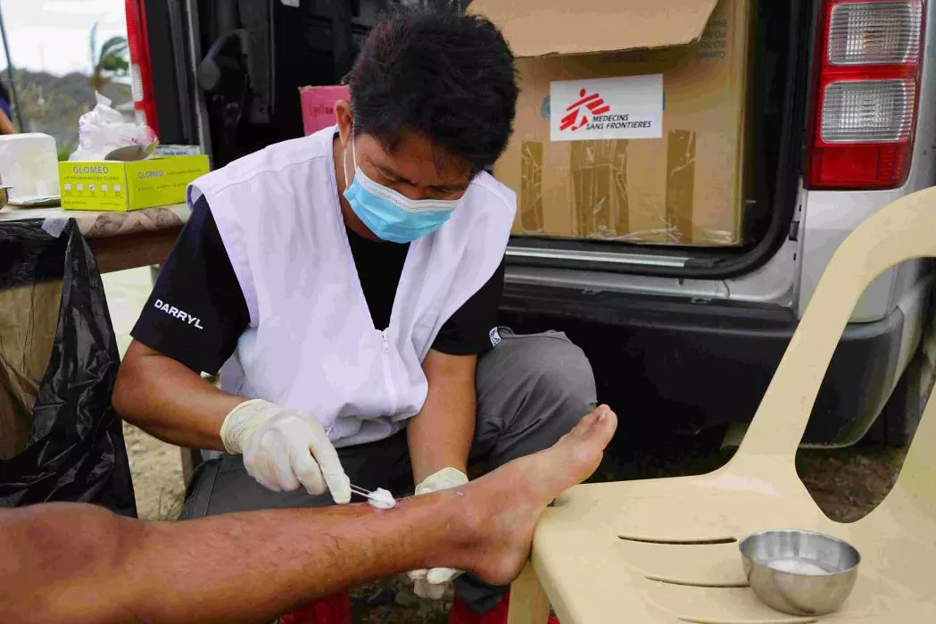 Nurse cleans a leg wound on a teenaged boy.