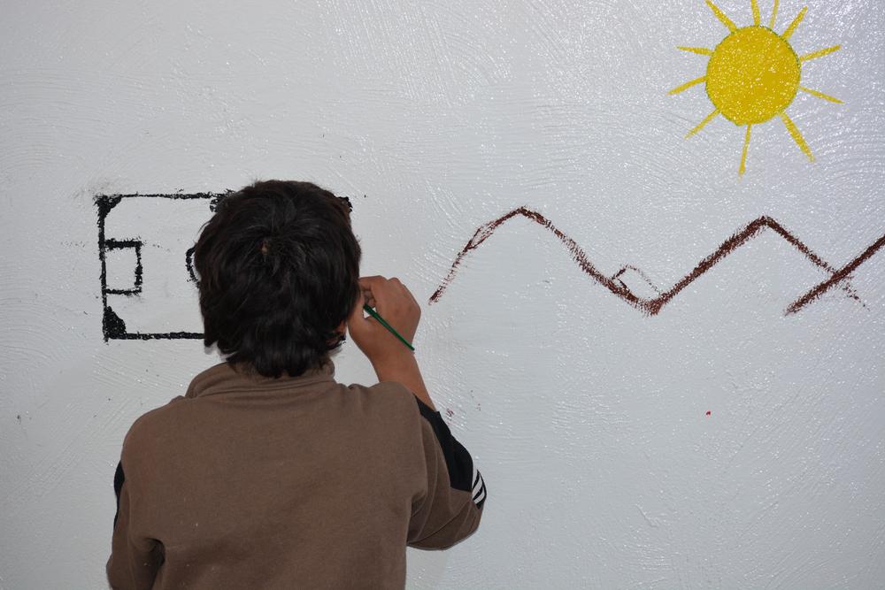 A teenager draws on the wall at MSF’s mental health clinic in Al-Hol camp