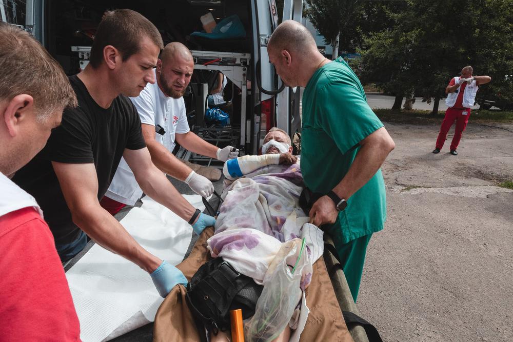 A patient with broken ribs and burns on his legs and hands is being prepared for transport.