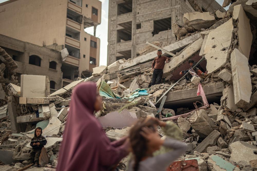 A woman and her children are trying to dig up their belongings from beneath the rubble