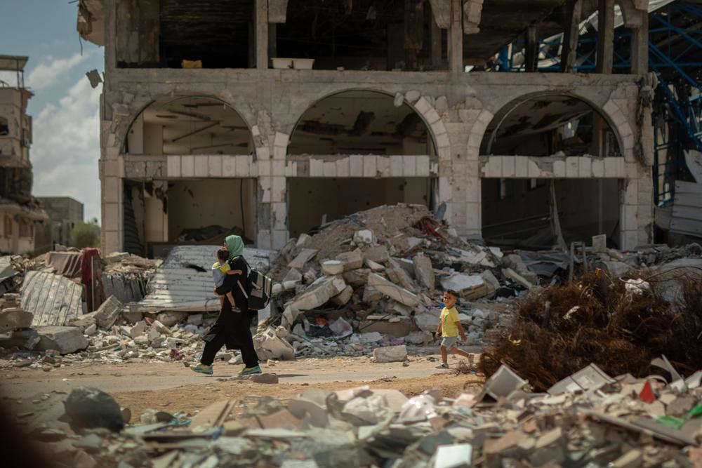 A woman is carrying her child back home through the rubble in Gaza City.