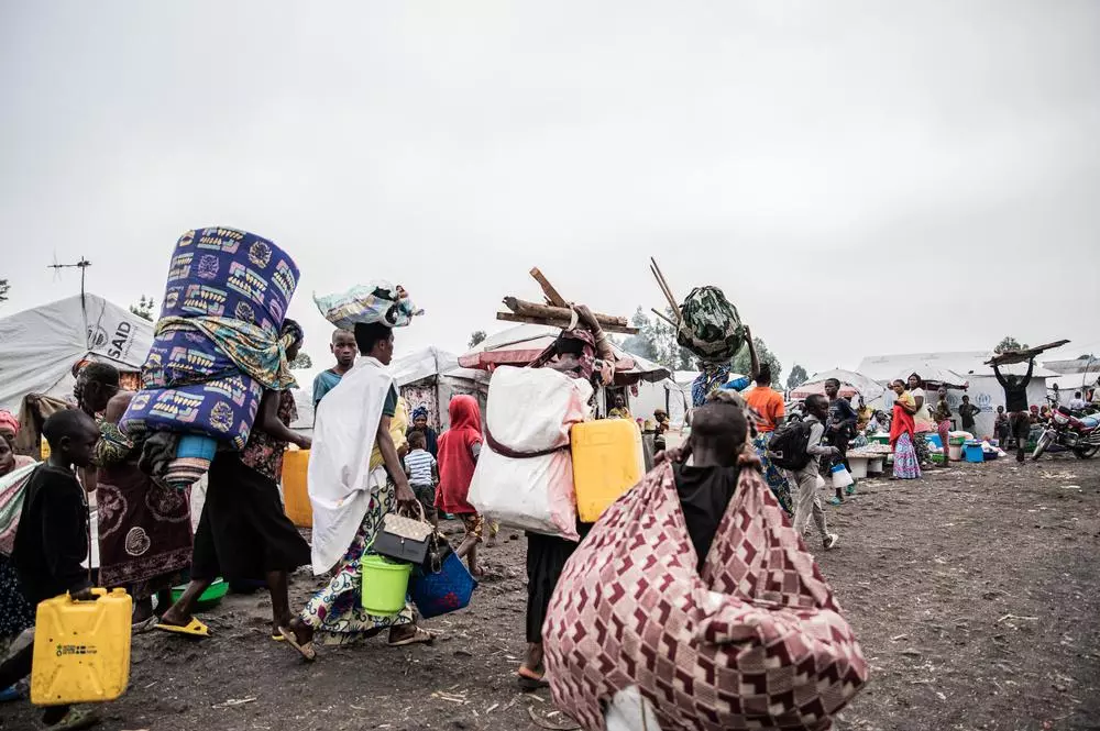 Families leave the Lushagala and Bulengo camps, carrying their packages on their backs and heads.
