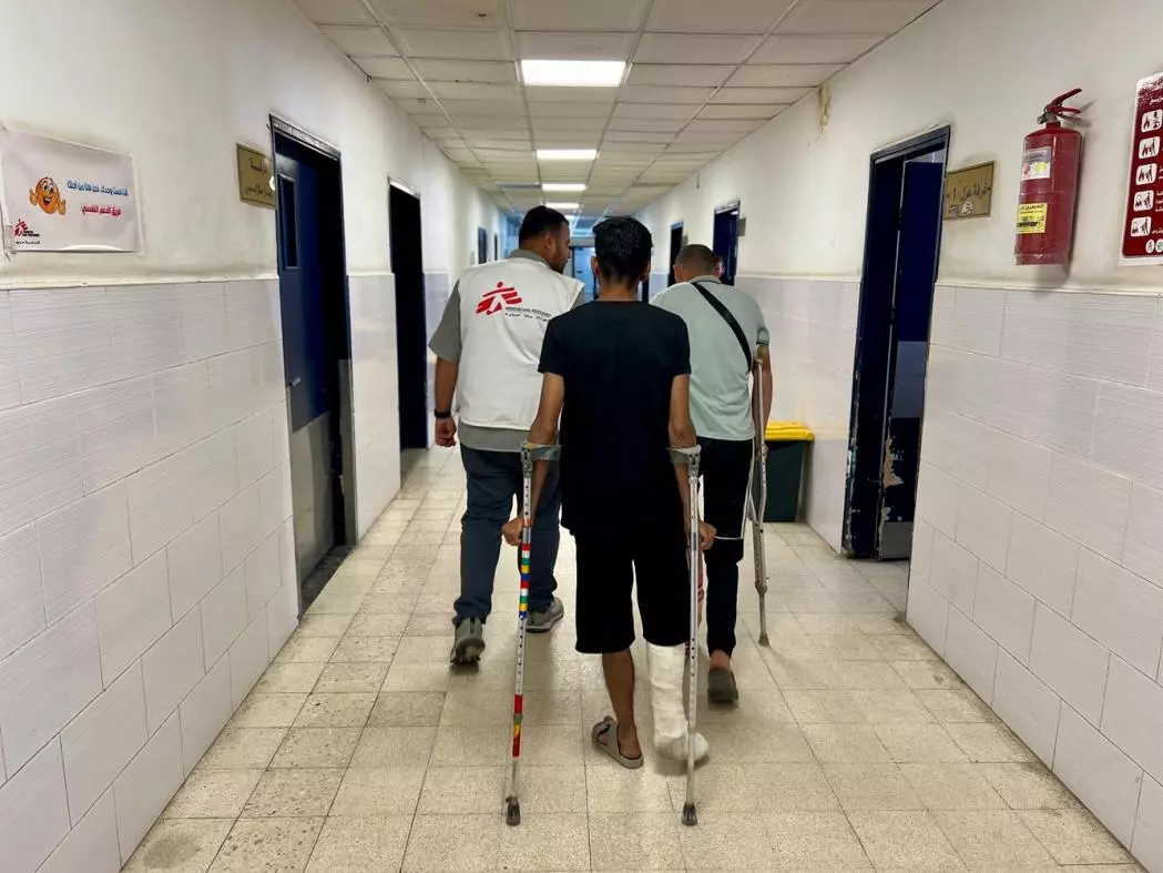 Two patients on crutches with MSF staff in a hospital