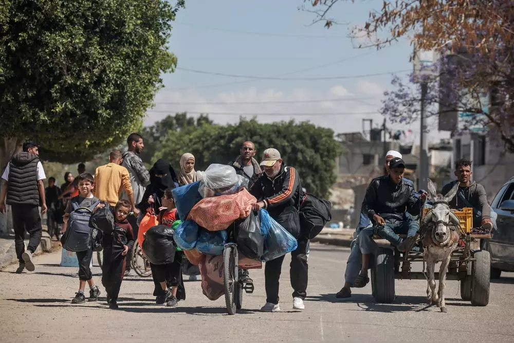 Displaced Palestinians carry their belongings