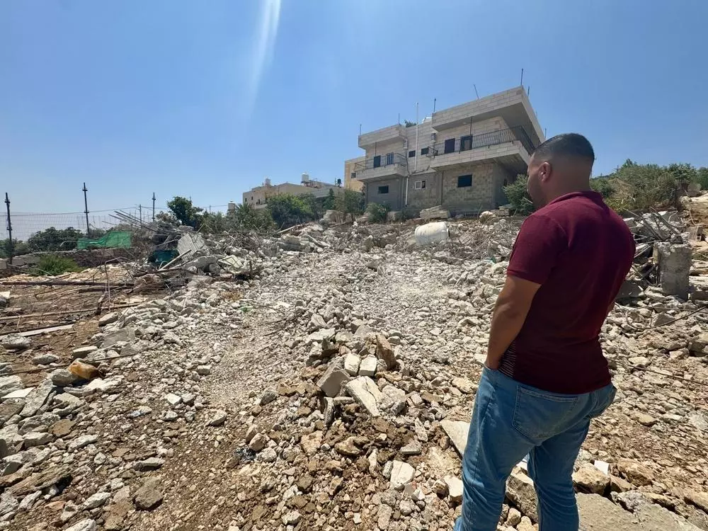 West Bank resident looking at rubble